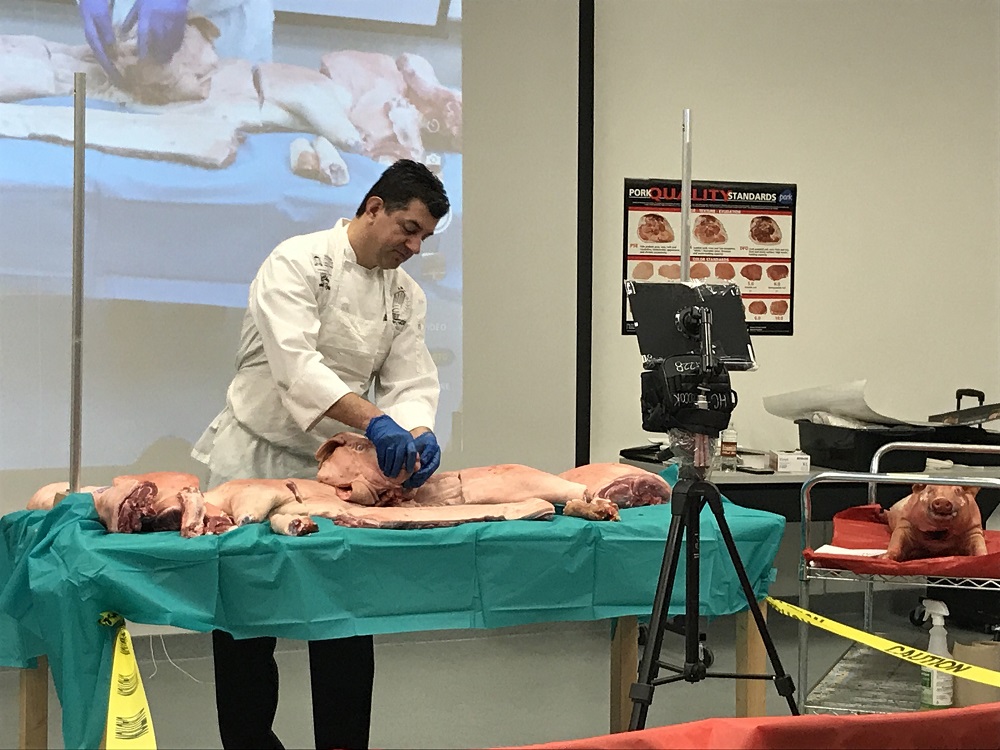 Cooking instructors come to Hillcrest High School to explain the pork preparation process to students.